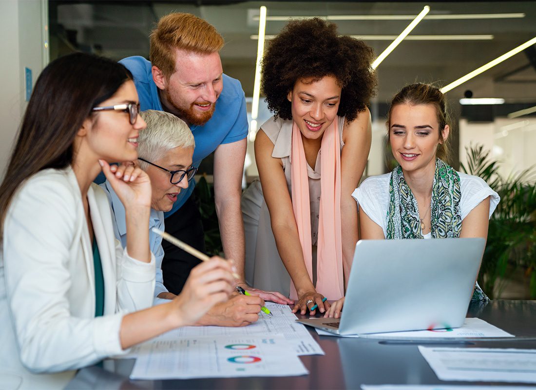 HR Resources - Small Group of Cheerful Employees During a Meeting in the Office Looking at Printed Graphics and a Laptop