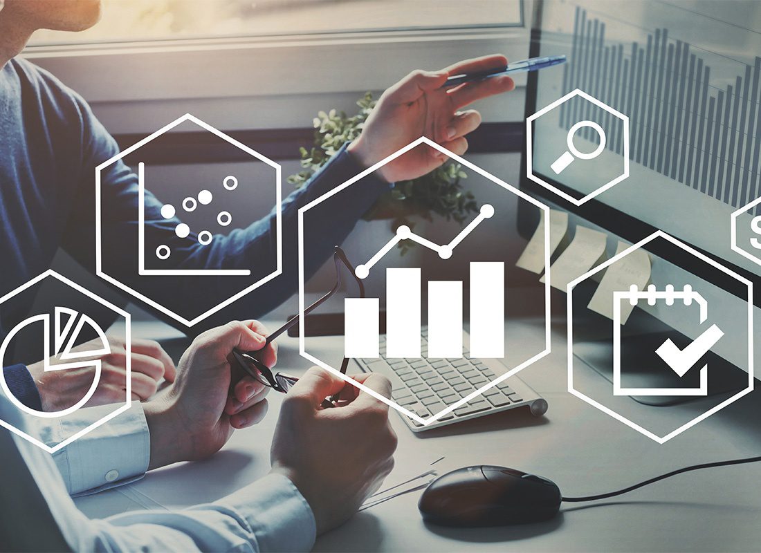 The Watkins Model - Two Businessmen Analyzing Data and Finances While Looking at a Computer in the Office with Financial Icon Illustrations On Top