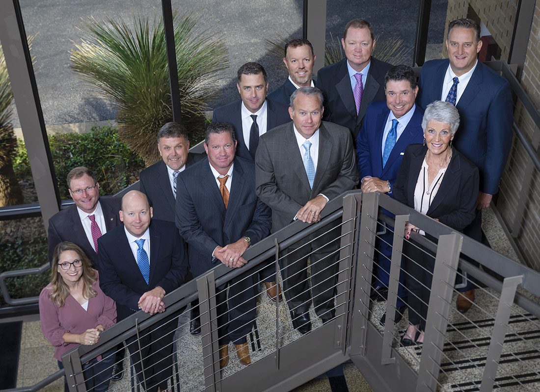 Who We Are - Portrait of a Smiling Group of Shareholders Part of Watkins Insurance Group Standing on the Steps Outside of an Office Building